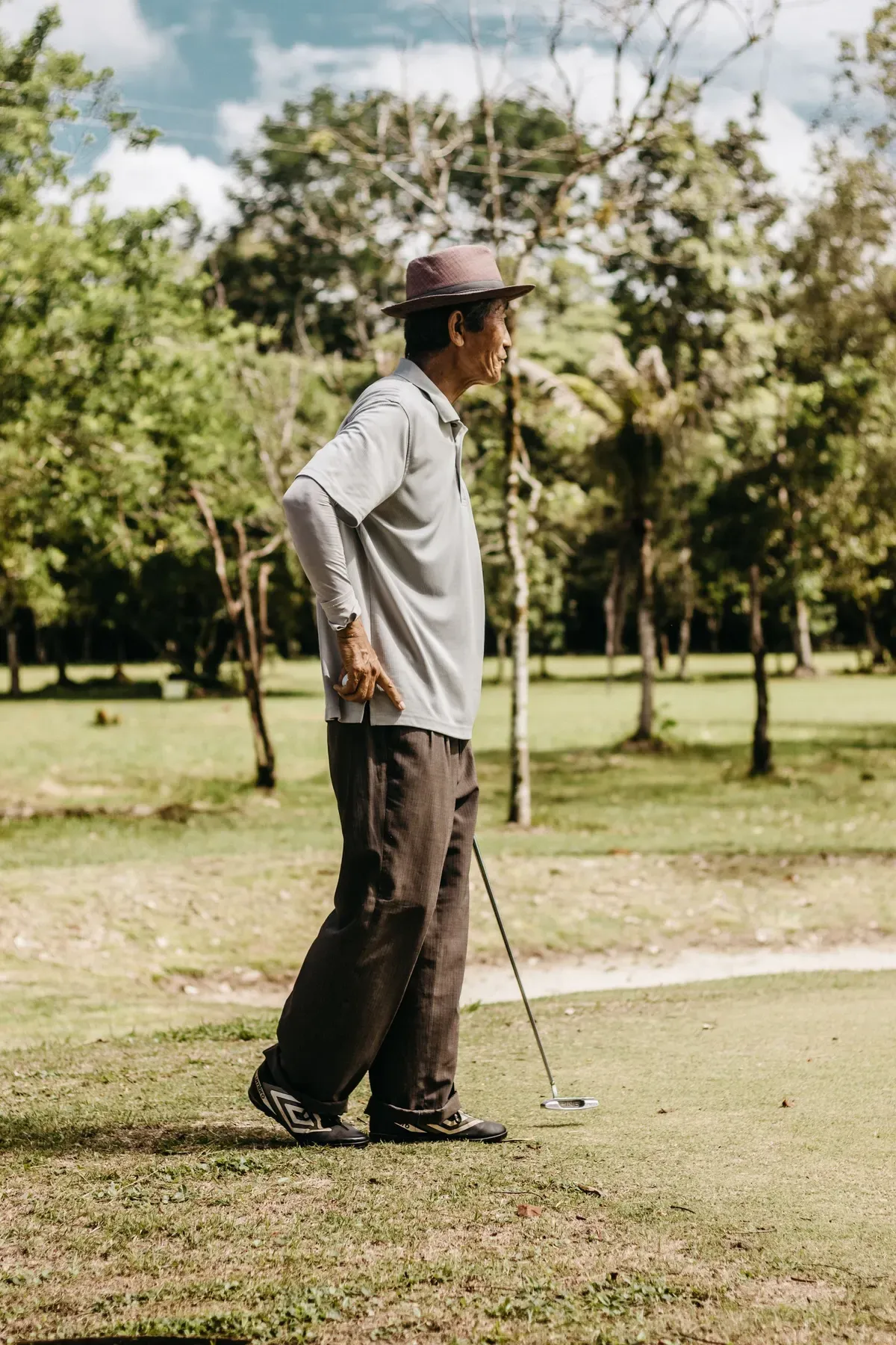 A golfer concentrating over a putt on a tree-lined green